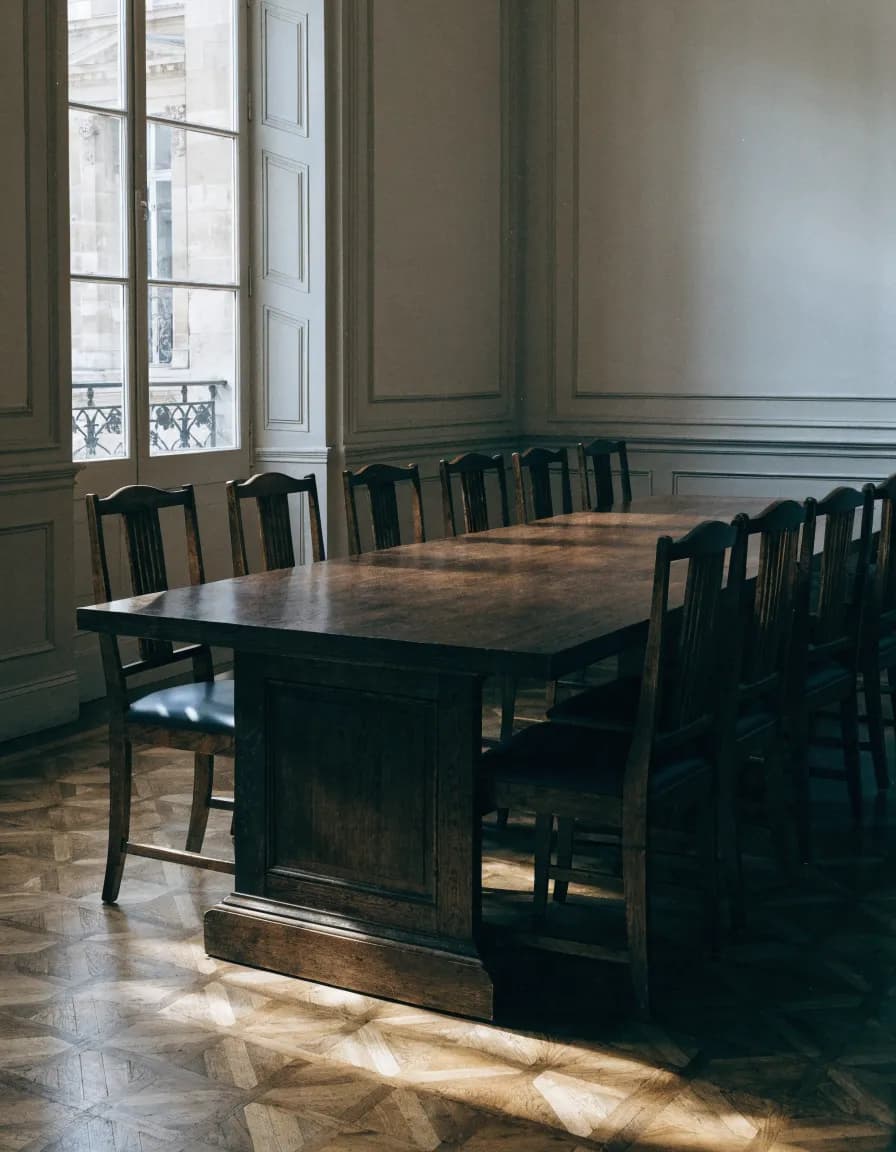 Vue intérieure d'un bureau en lumière naturelle, table de travail nue et cloison vitrée.